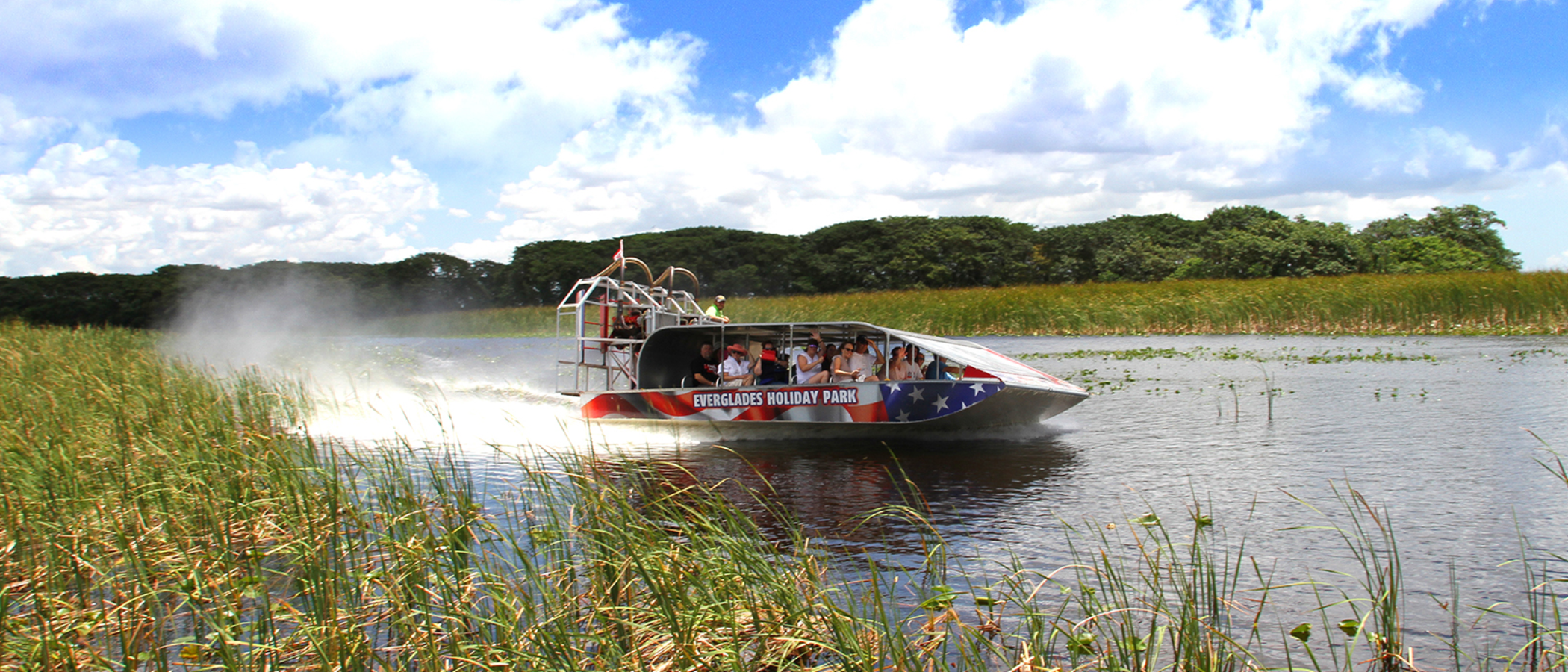 Airboat speeding through a marsh with passengers on board.